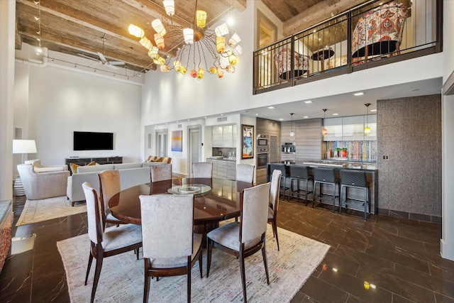 dining area with a towering ceiling, beam ceiling, and a chandelier