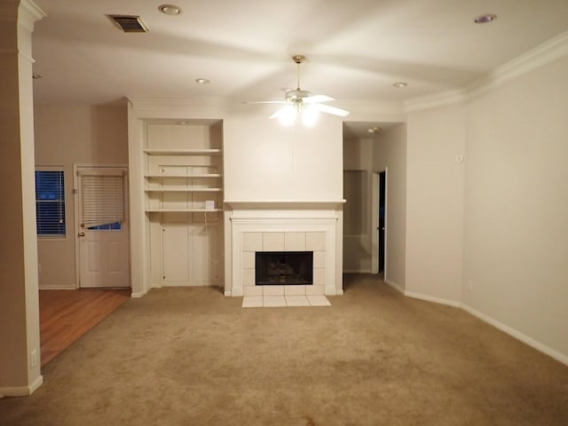 unfurnished living room featuring a tiled fireplace, crown molding, light carpet, and ceiling fan