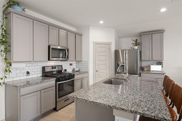 kitchen with appliances with stainless steel finishes, a kitchen bar, a kitchen island with sink, and sink