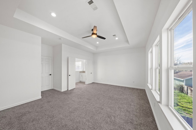 unfurnished bedroom with a tray ceiling and carpet