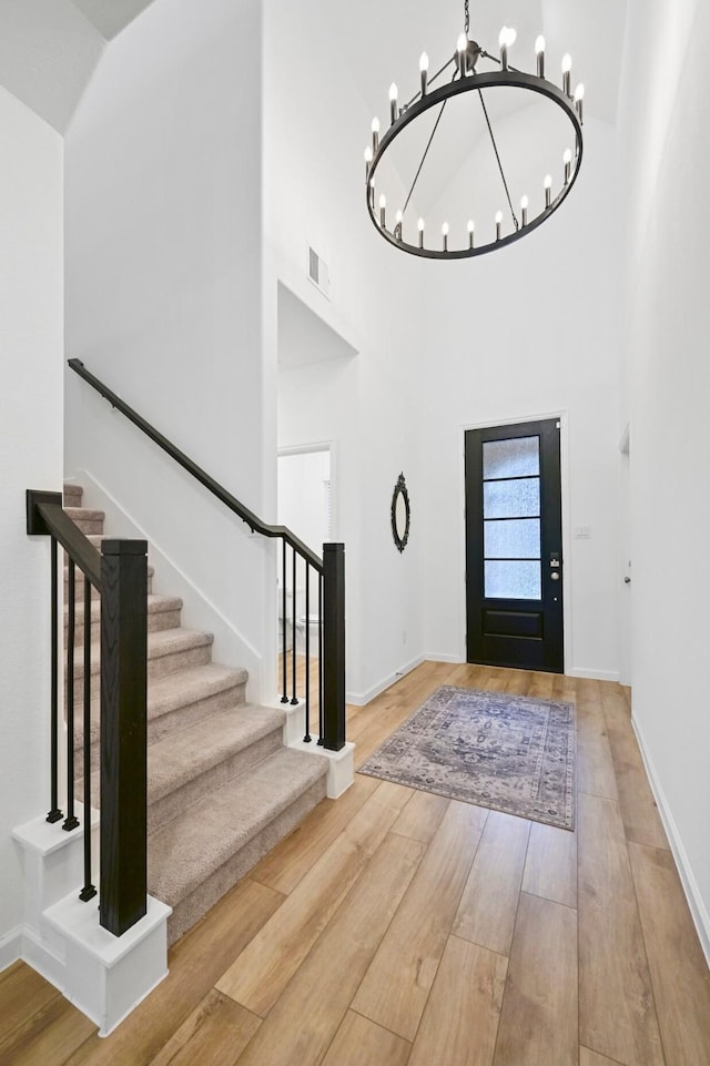 foyer featuring a notable chandelier, a towering ceiling, and wood-type flooring