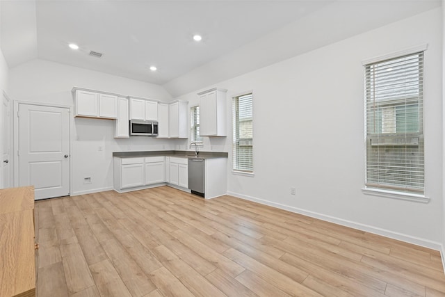 kitchen with vaulted ceiling, stainless steel appliances, light wood-type flooring, and white cabinets