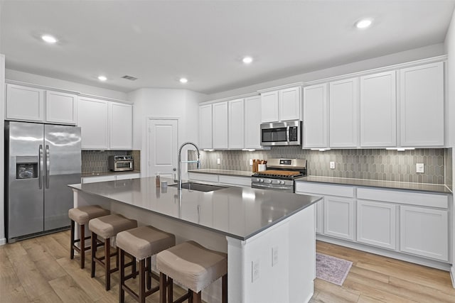 kitchen with sink, white cabinetry, a center island with sink, a kitchen breakfast bar, and stainless steel appliances