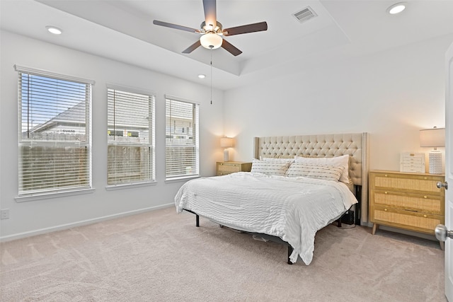 bedroom with ceiling fan, light colored carpet, and a raised ceiling