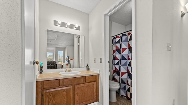 bathroom featuring vanity, walk in shower, a textured ceiling, and toilet