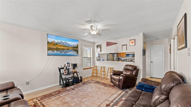 living room featuring ceiling fan, hardwood / wood-style floors, and a textured ceiling