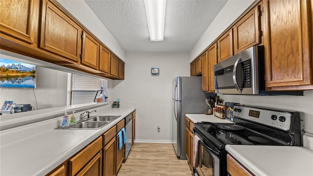 kitchen featuring sink, stainless steel appliances, a textured ceiling, and light wood-type flooring