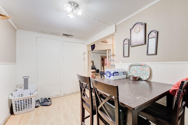 dining space with light hardwood / wood-style flooring and ornamental molding