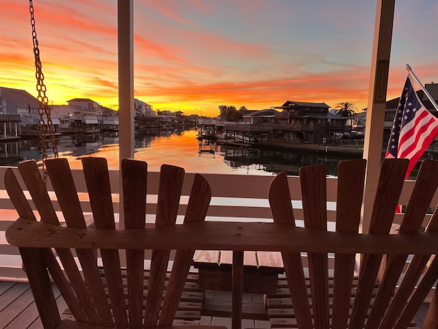 deck at dusk featuring a water view