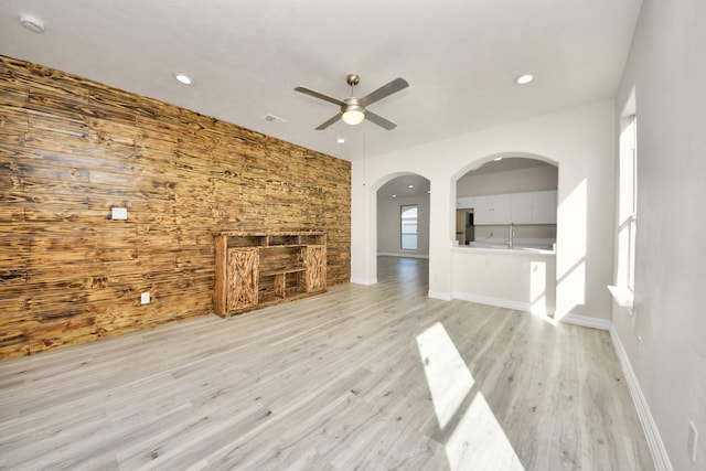 unfurnished living room featuring sink, light hardwood / wood-style flooring, and ceiling fan