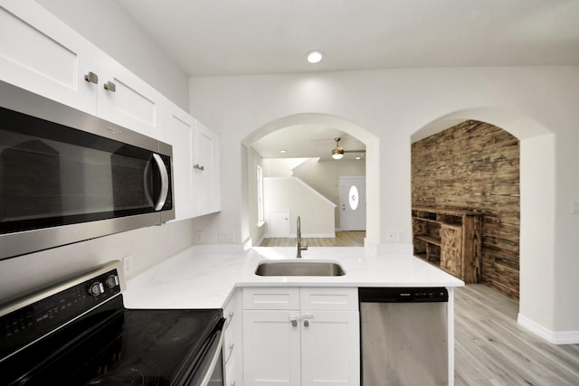 kitchen with appliances with stainless steel finishes, sink, white cabinets, ceiling fan, and light wood-type flooring