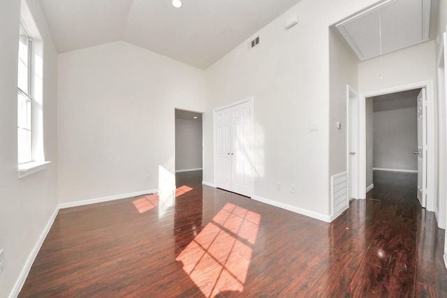 spare room with dark wood-type flooring and vaulted ceiling