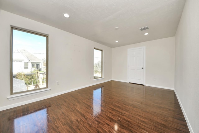 spare room featuring dark hardwood / wood-style floors and a textured ceiling