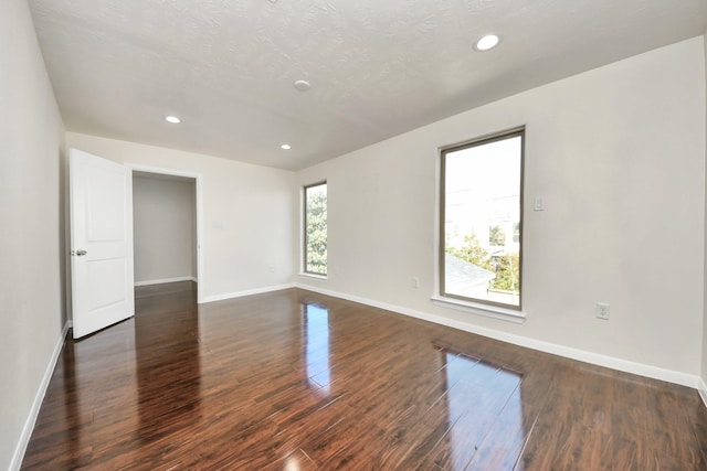 unfurnished room featuring dark wood-type flooring and a textured ceiling