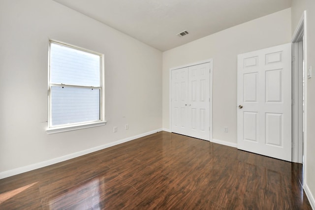 unfurnished bedroom with dark wood-type flooring and a closet