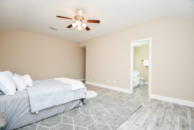 bedroom featuring vaulted ceiling, ceiling fan, light hardwood / wood-style floors, and ensuite bath