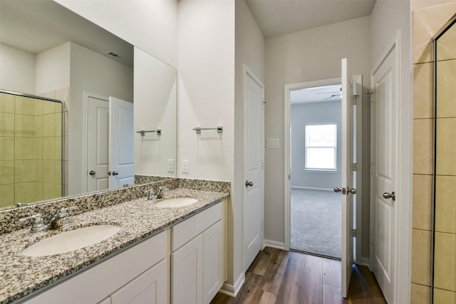 bathroom with walk in shower, vanity, and hardwood / wood-style floors