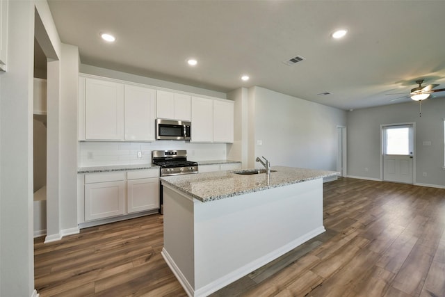 kitchen featuring appliances with stainless steel finishes, sink, white cabinets, dark hardwood / wood-style flooring, and a center island with sink