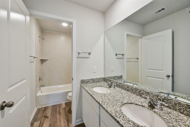 full bathroom featuring tiled shower / bath, wood-type flooring, toilet, and vanity