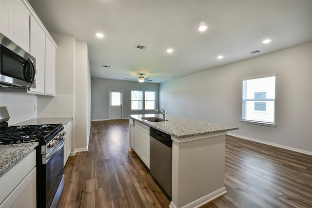 kitchen featuring sink, appliances with stainless steel finishes, a kitchen island with sink, white cabinetry, and light stone counters