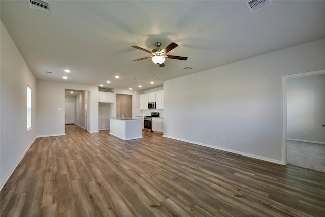 unfurnished living room featuring hardwood / wood-style flooring, sink, and ceiling fan