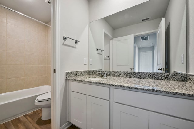 full bathroom with vanity, tiled shower / bath combo, wood-type flooring, and toilet