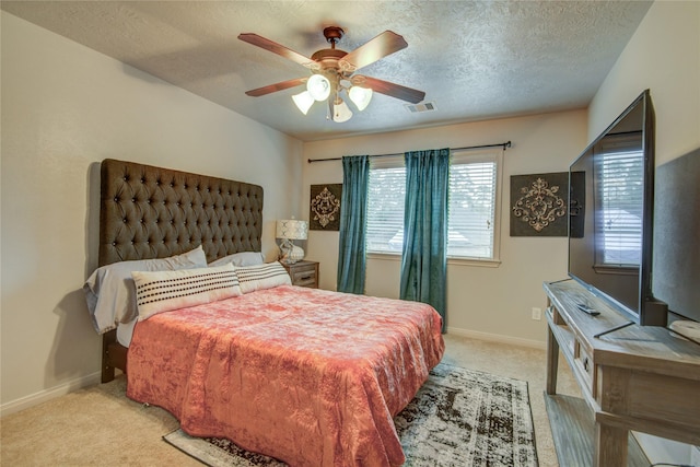 bedroom featuring ceiling fan, light colored carpet, and a textured ceiling