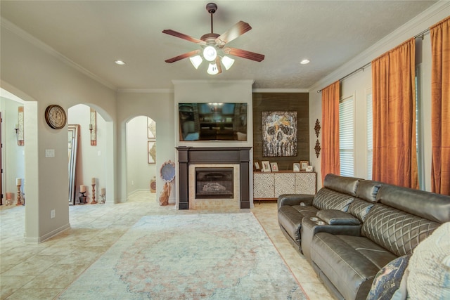 living room featuring a tiled fireplace, ornamental molding, and ceiling fan