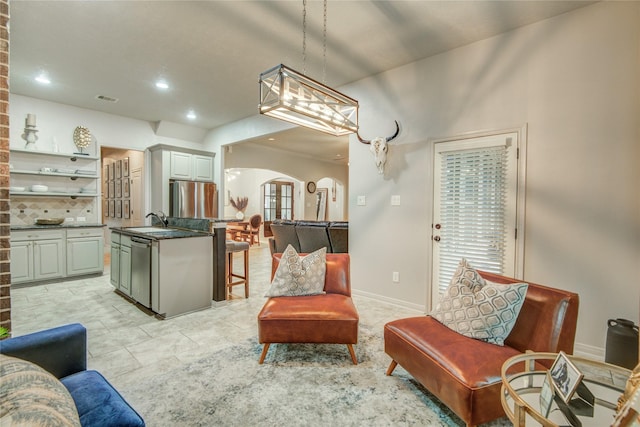 interior space featuring sink, gray cabinetry, decorative light fixtures, appliances with stainless steel finishes, and a kitchen island