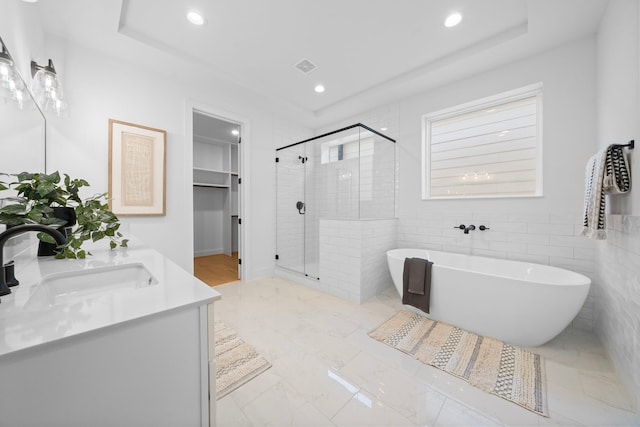 bathroom featuring vanity, shower with separate bathtub, and tile walls