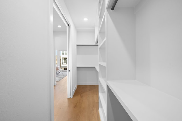 walk in closet with light hardwood / wood-style floors