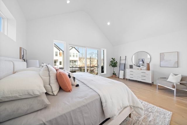 bedroom featuring access to exterior, light hardwood / wood-style floors, and high vaulted ceiling