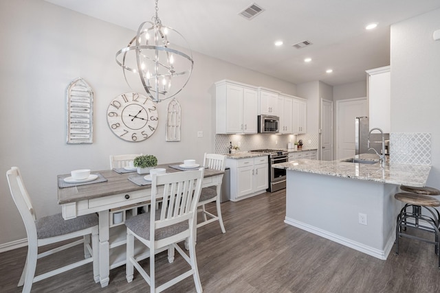 kitchen featuring sink, appliances with stainless steel finishes, light stone countertops, white cabinets, and kitchen peninsula