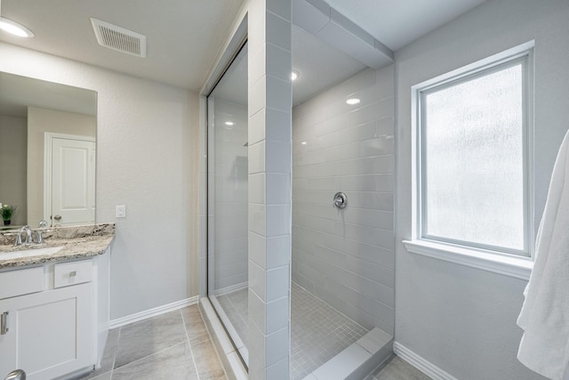 bathroom featuring a tile shower, vanity, and tile patterned flooring