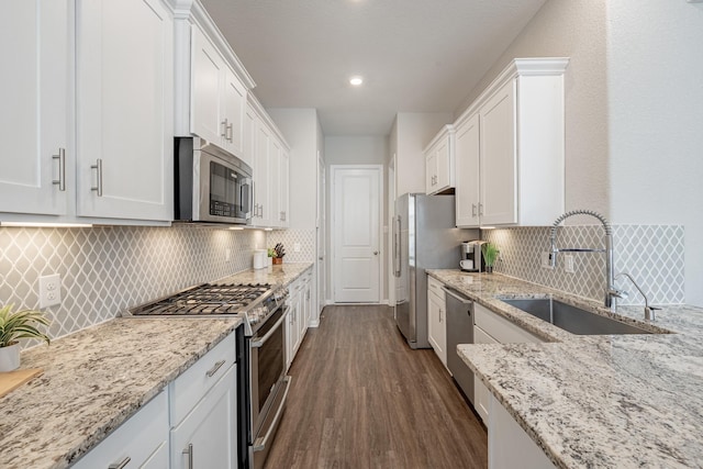 kitchen with sink, light stone counters, dark hardwood / wood-style flooring, stainless steel appliances, and white cabinets