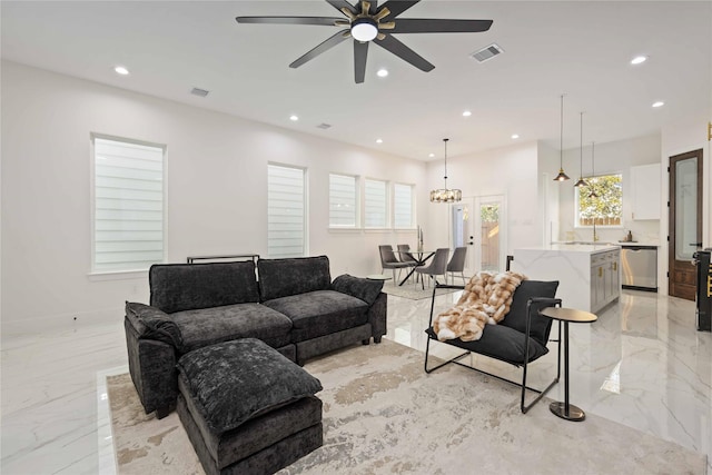 living room featuring sink and ceiling fan with notable chandelier