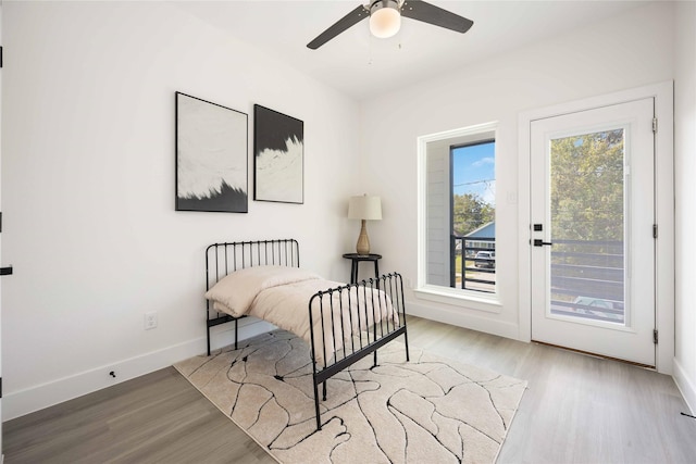 bedroom featuring multiple windows, access to exterior, ceiling fan, and light wood-type flooring