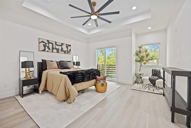 bedroom with light hardwood / wood-style flooring, a raised ceiling, ceiling fan, and access to outside