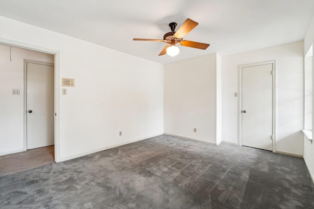 empty room with dark colored carpet and ceiling fan