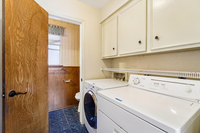 laundry area with cabinets, separate washer and dryer, and wooden walls