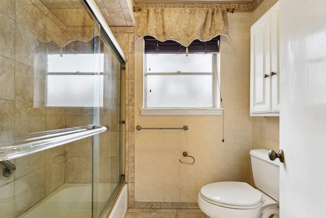 bathroom with tile patterned flooring, enclosed tub / shower combo, and toilet