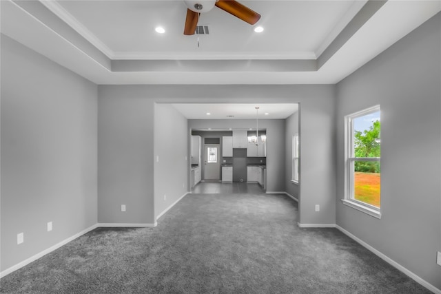 unfurnished living room with crown molding, a tray ceiling, and dark colored carpet