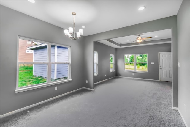 empty room with ceiling fan with notable chandelier, a tray ceiling, and carpet floors