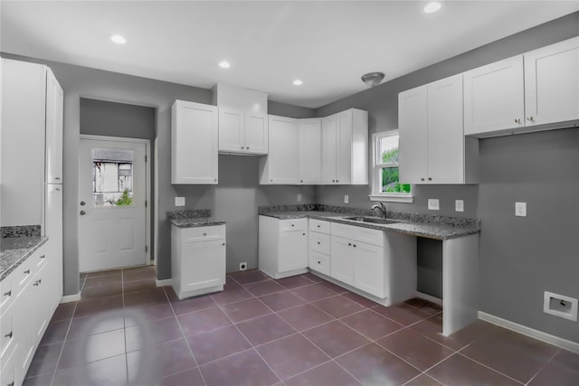 kitchen with white cabinetry, sink, dark tile patterned floors, and stone counters