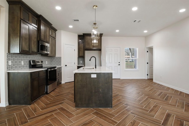 kitchen with sink, appliances with stainless steel finishes, backsplash, dark parquet flooring, and a center island with sink