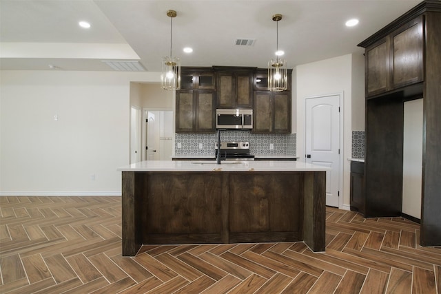 kitchen with appliances with stainless steel finishes, dark parquet floors, pendant lighting, and dark brown cabinetry