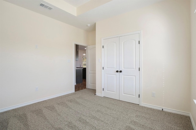 unfurnished bedroom with light colored carpet and a closet