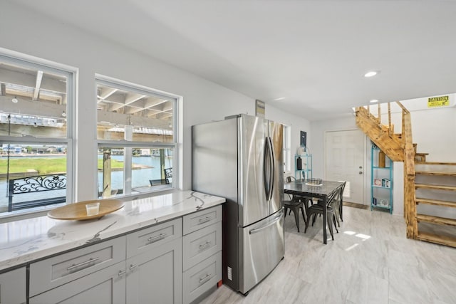 kitchen featuring gray cabinets, light stone counters, and stainless steel refrigerator