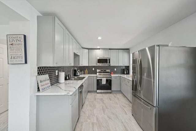 kitchen with gray cabinets, appliances with stainless steel finishes, sink, and backsplash