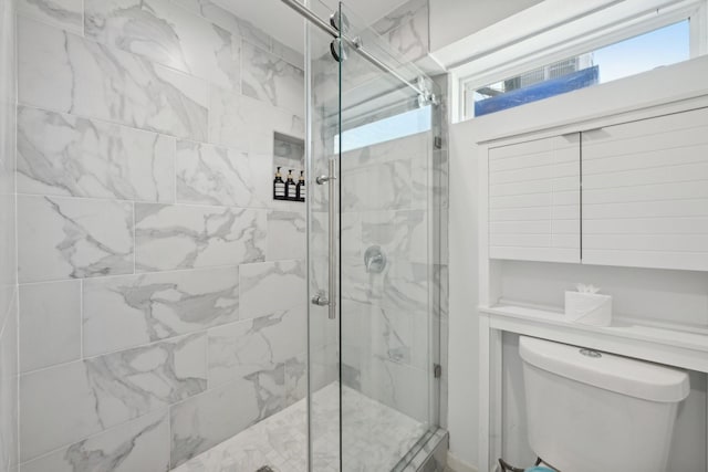 bathroom featuring a shower with door and toilet